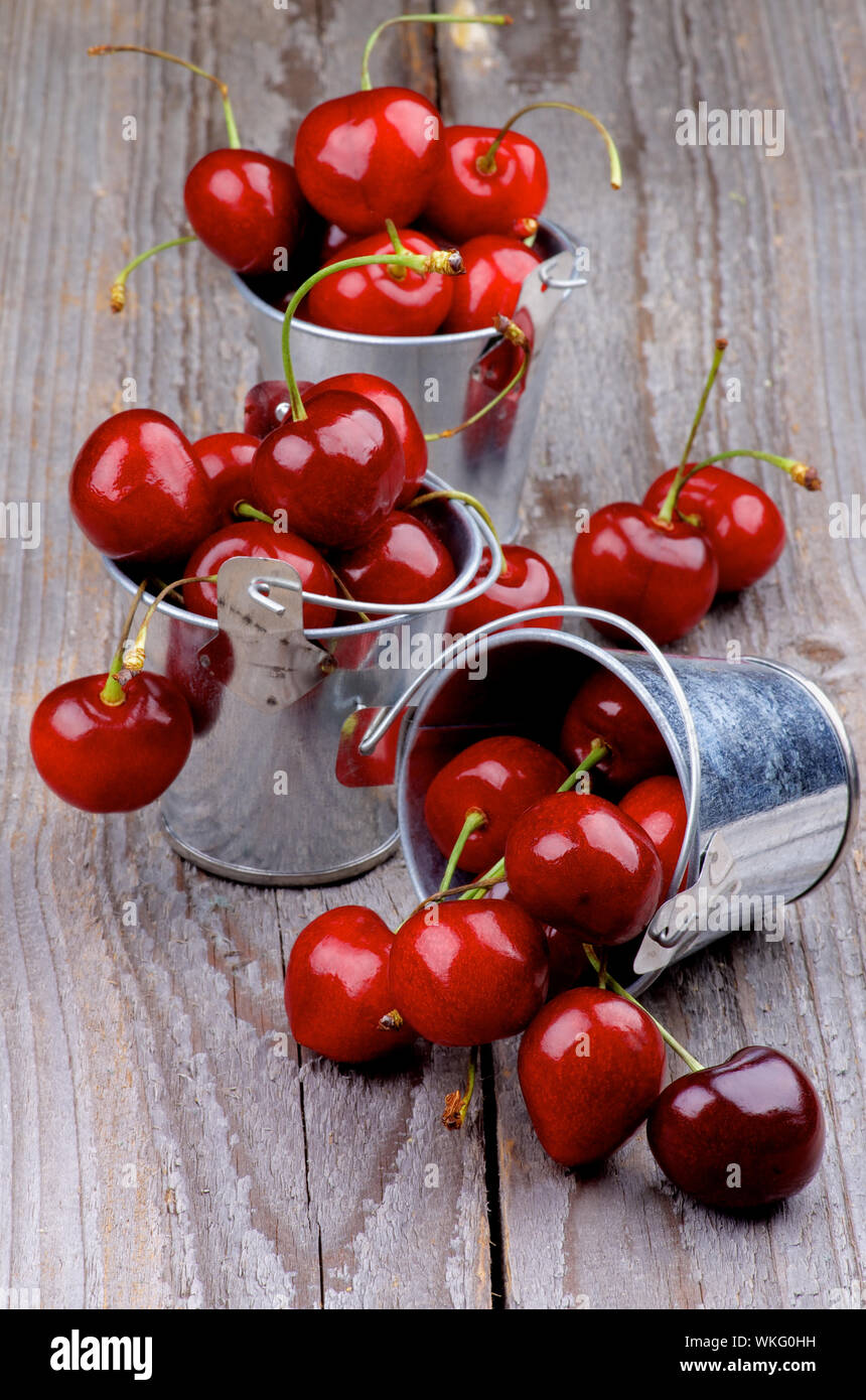Seaux en étain avec des cerises mûres isolé sur fond de bois rustique Banque D'Images