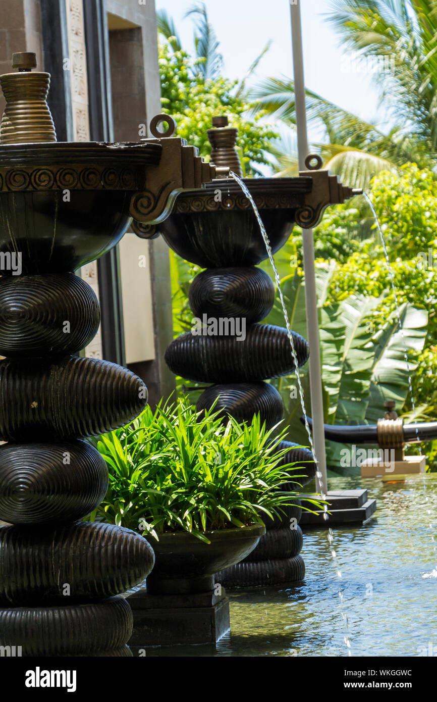 Fontaine ornementale dans un étang peu profond dans un parc à l'extérieur  d'un bâtiment ou maison à Bali avec des jets d'eau dans la piscine en  cascade ci-dessous et Photo Stock -