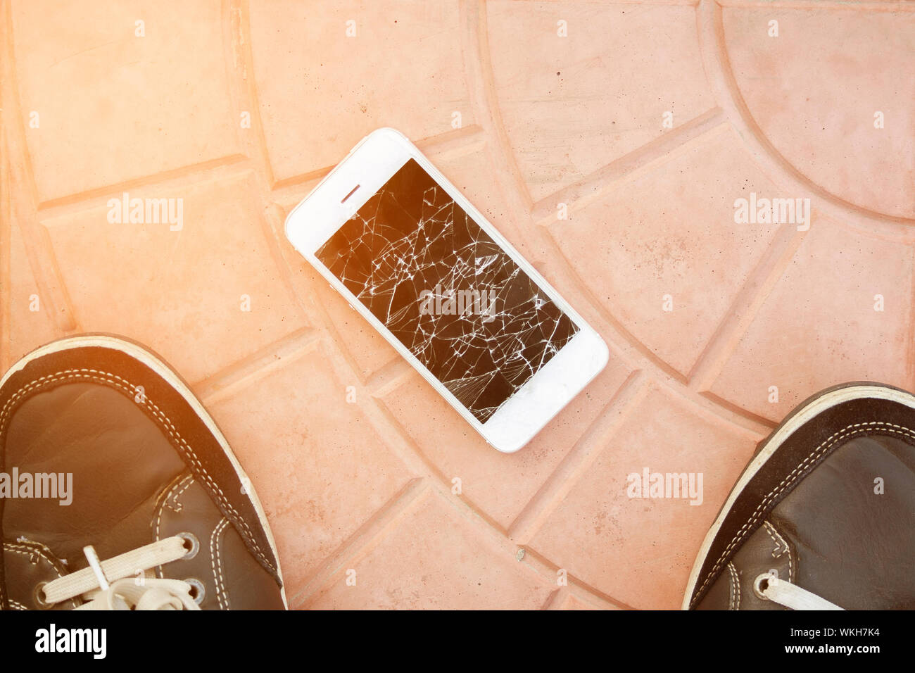 Casse de l'écran du smartphone. Pieds et smartphone sur le sol carrelé. Vue d'en haut téléphone cassé Banque D'Images