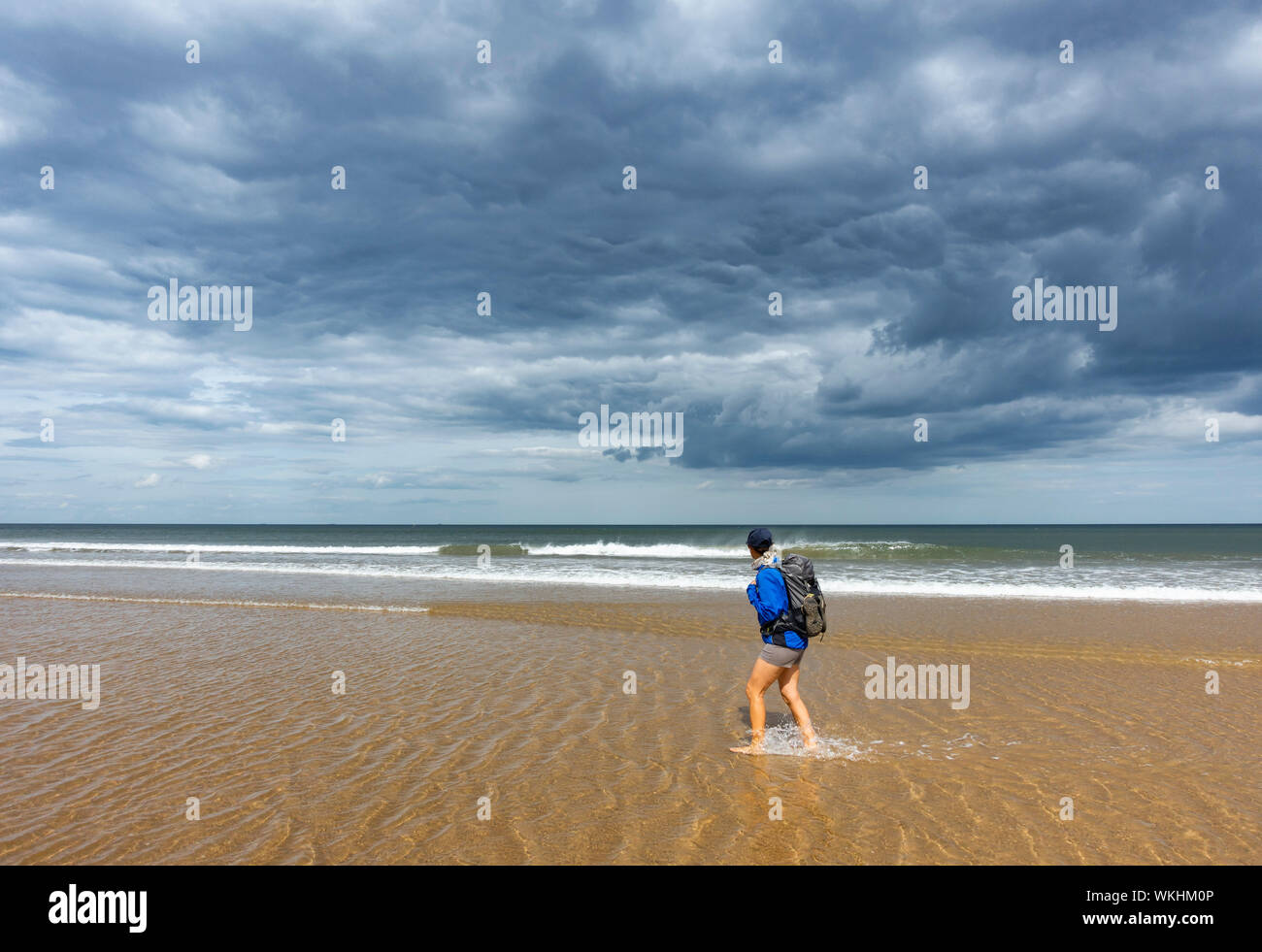 Une femelle marchant sur la plage sous un ciel orageux sur le sentier de la côte d'Angleterre à Saltburn, sur la côte du Yorkshire. ROYAUME-UNI Banque D'Images