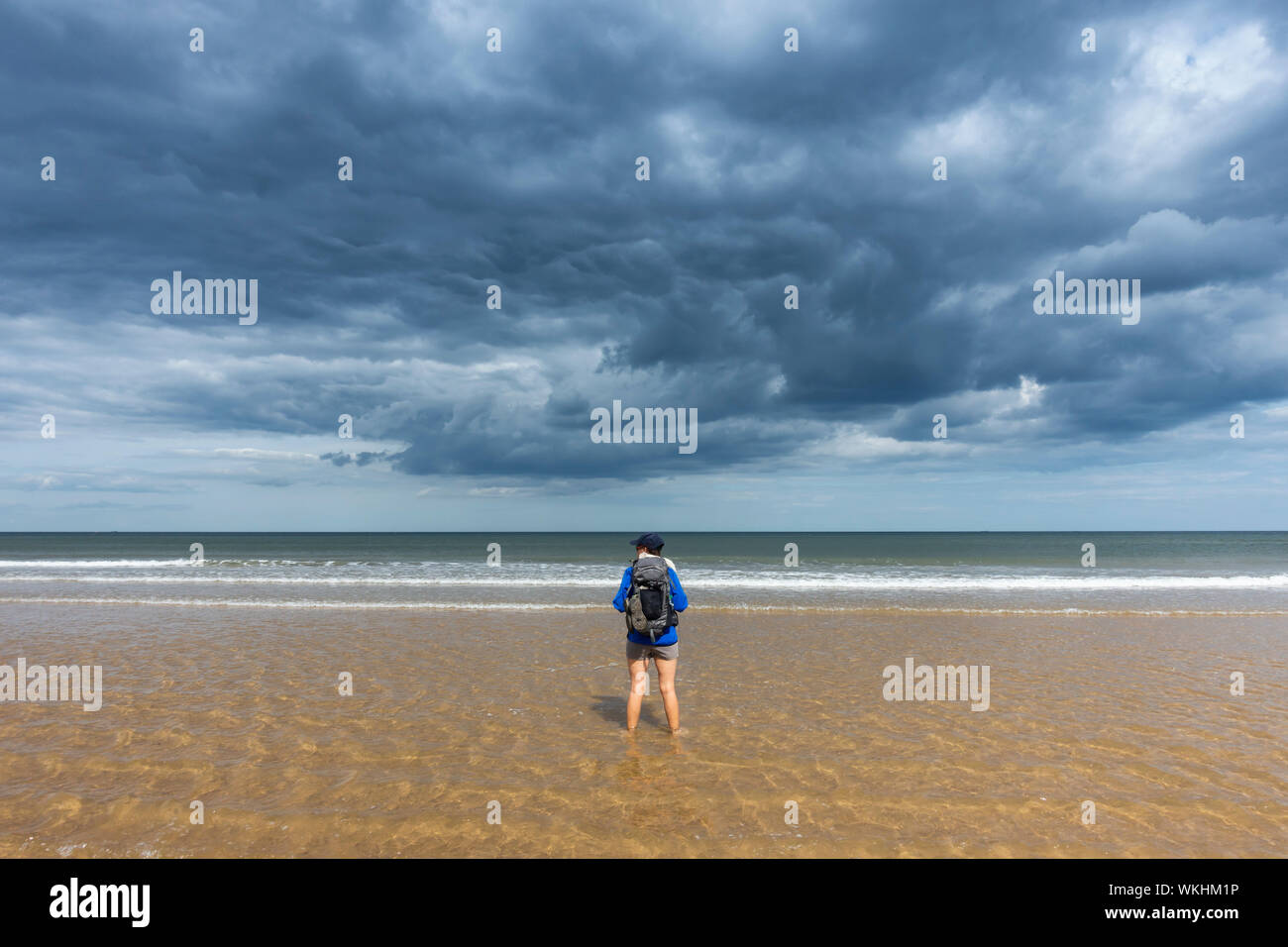 Une femelle marchant sur la plage sous un ciel orageux sur le sentier de la côte d'Angleterre à Saltburn, sur la côte du Yorkshire. ROYAUME-UNI Banque D'Images
