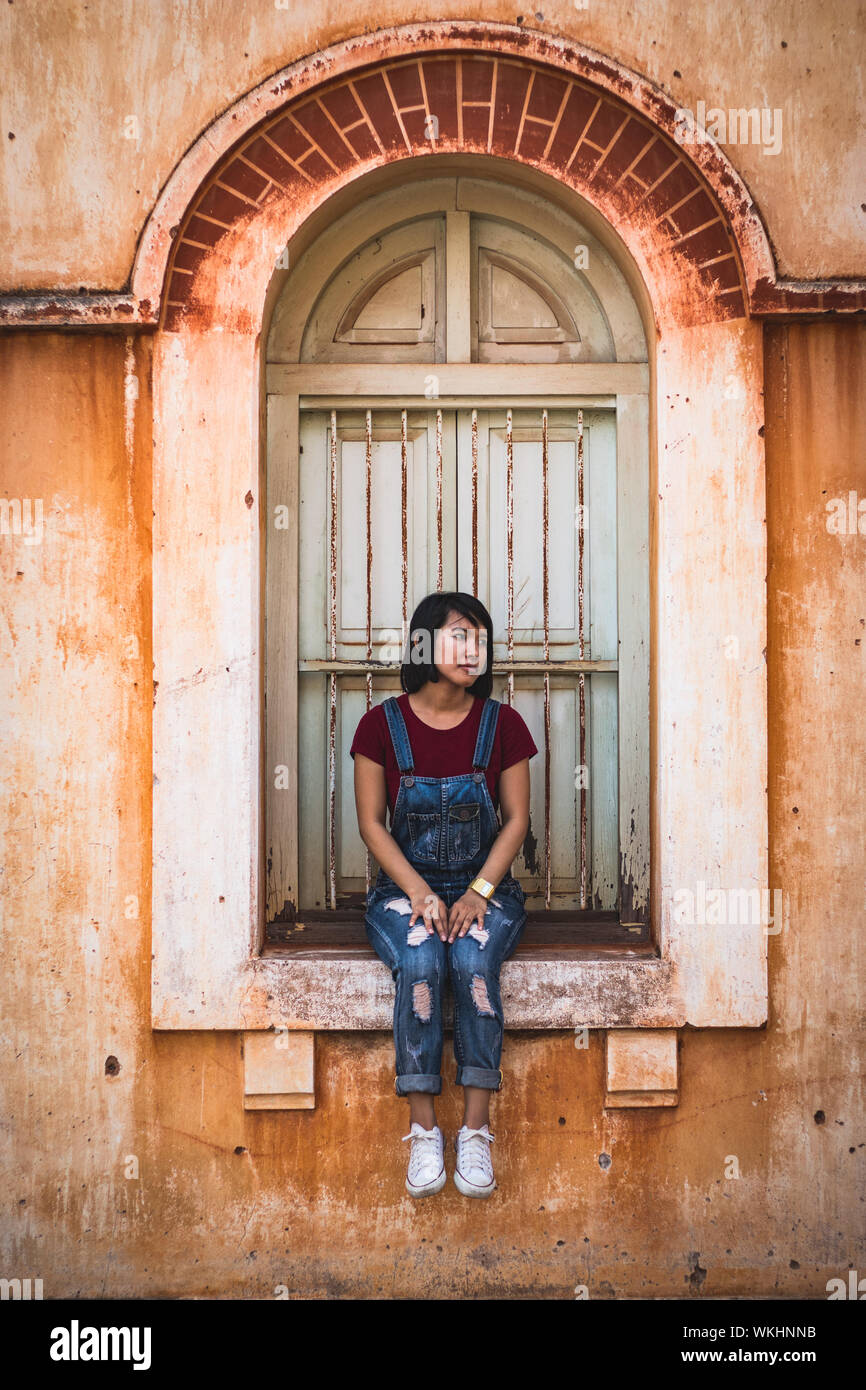 Toute la longueur de Jeune femme assise sur le rebord de fenêtre dans l