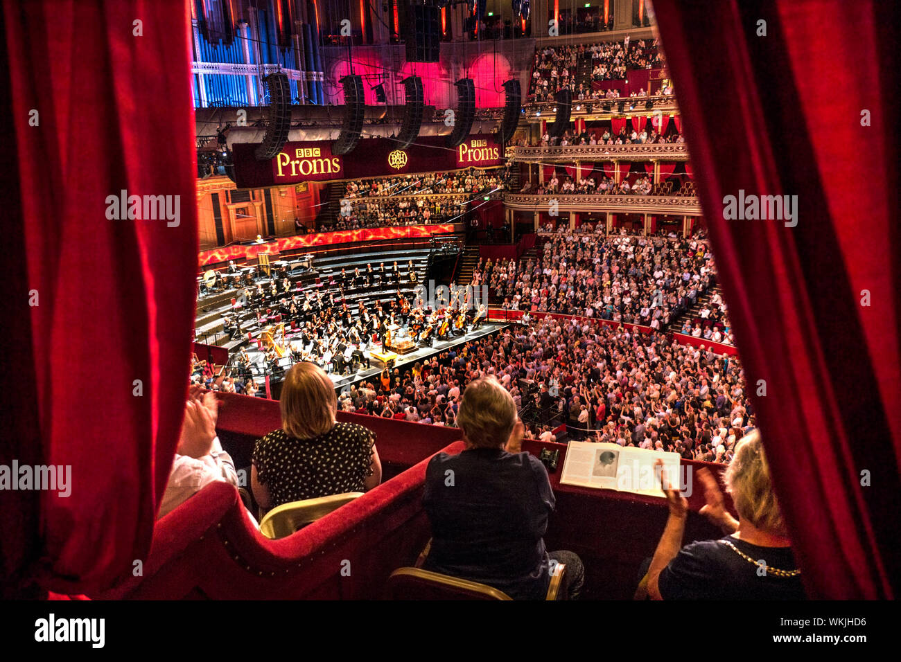 ALBERT HALL INTÉRIEUR Performance BBC Proms avec public applaudissant des mains, Sheku Kanneh-Mason violoncelliste britannique en tenant un arc view de velours rouge de luxe privée à l'auditoire et l'étape de l'orchestre derrière Londres UK dais Banque D'Images
