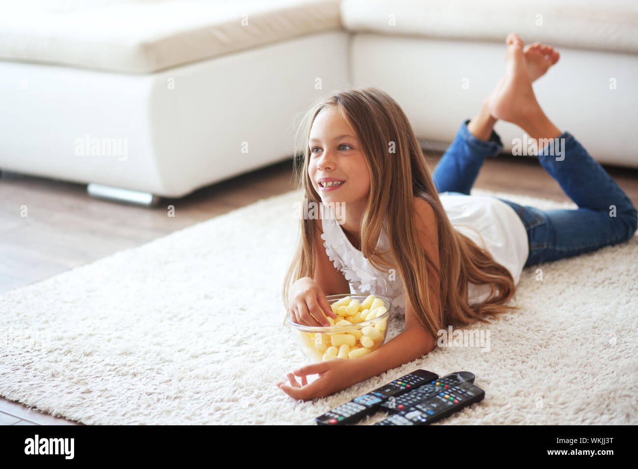 8 Ans Enfant Regarder La Télévision Fixant Sur Un Tapis Blanc Seul