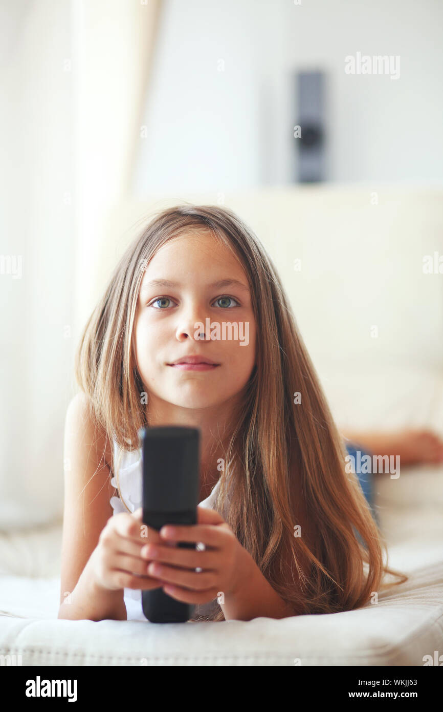 Enfant de 8 ans regarder la télévision allongé sur un canapé à la maison Banque D'Images