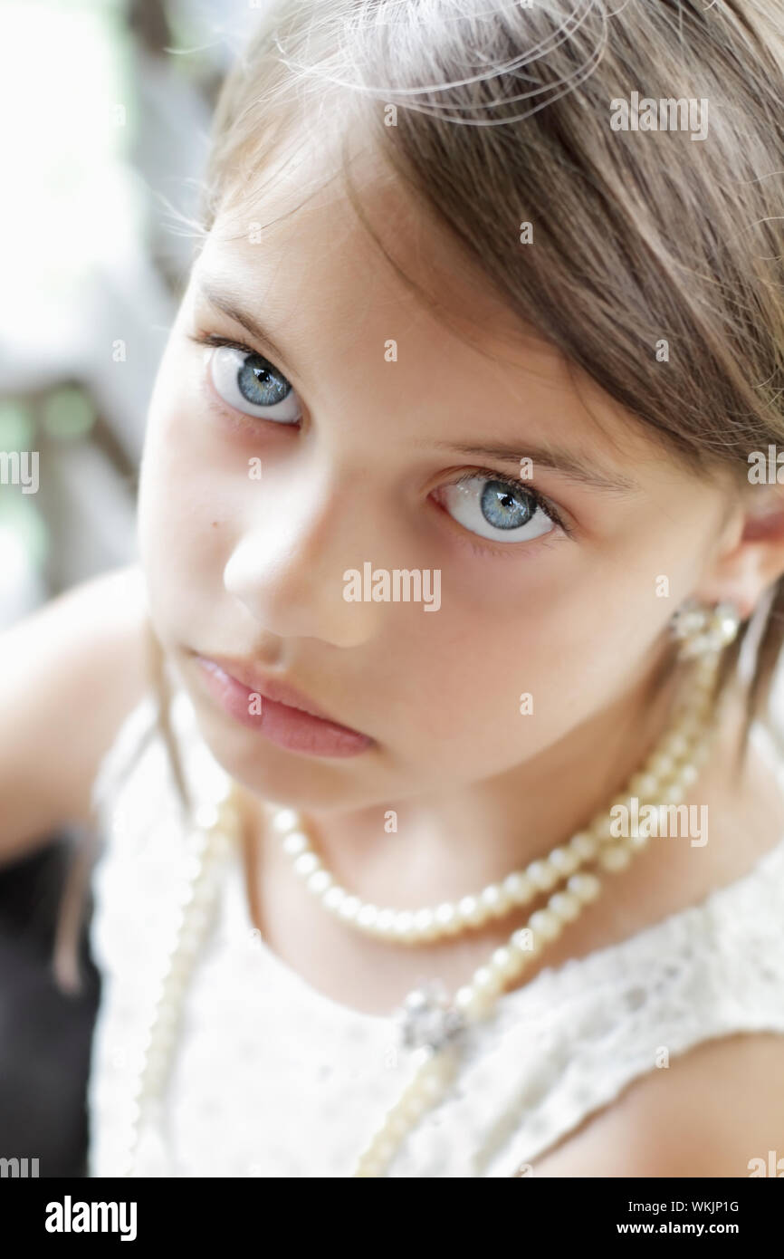 Jeune fille à la recherche directement dans l'appareil photo, le port vintage pearl collier et cheveux tirés en arrière. L'extrême profondeur de champ avec selective focus Banque D'Images