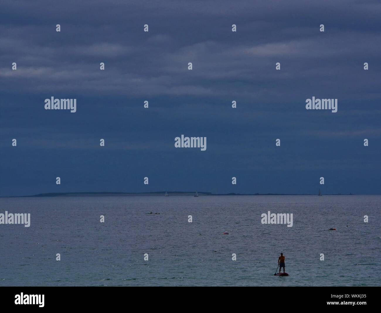 Le Stand Up Paddle dans l'océan en face de la plage de plouguerneau avec une île en fond , ciel couvert Banque D'Images