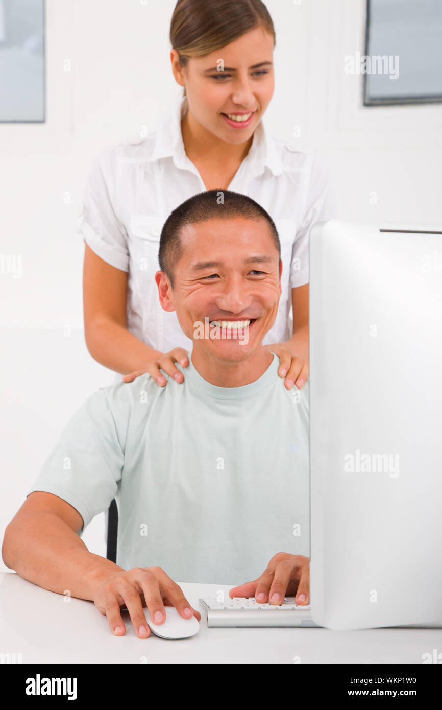 Happy woman debout derrière l'homme à l'aide d'ordinateur Banque D'Images