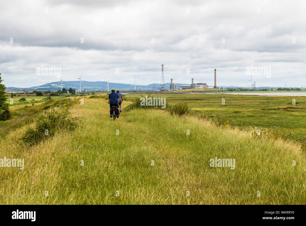 Uskmouth Power Station et deux cyclistes sur la côte du Pays de Galles sur le chemin South Wales Niveaux Gwent Banque D'Images