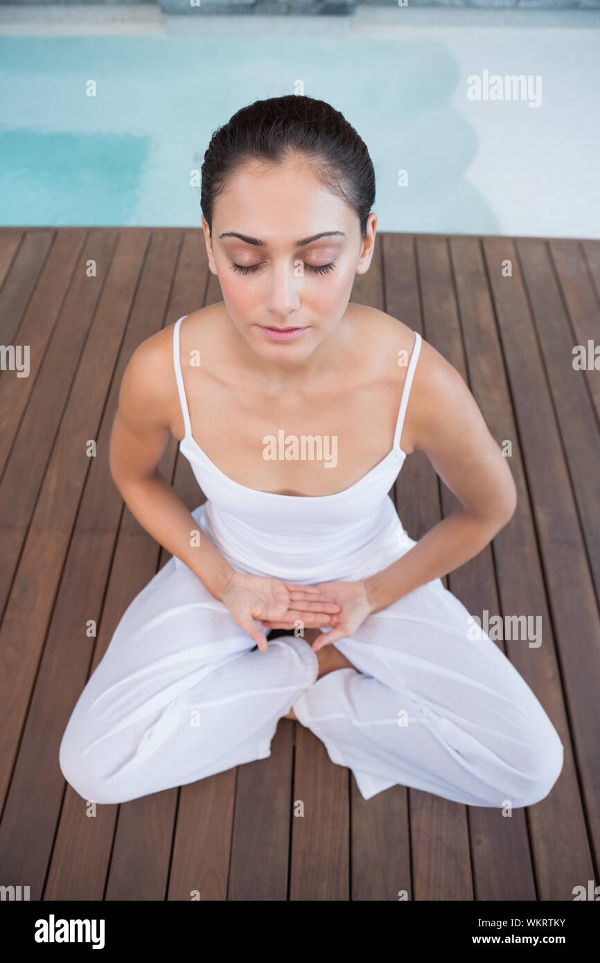 Brunette pacifiques en blanc assis en lotus de poser dans les health spa Banque D'Images