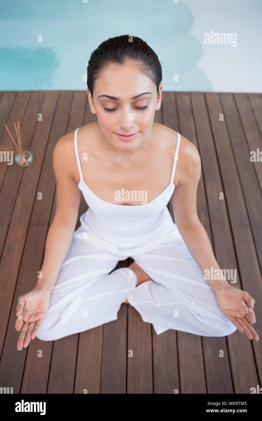 Brunette pacifiques en blanc assis en lotus de poser dans les health spa Banque D'Images