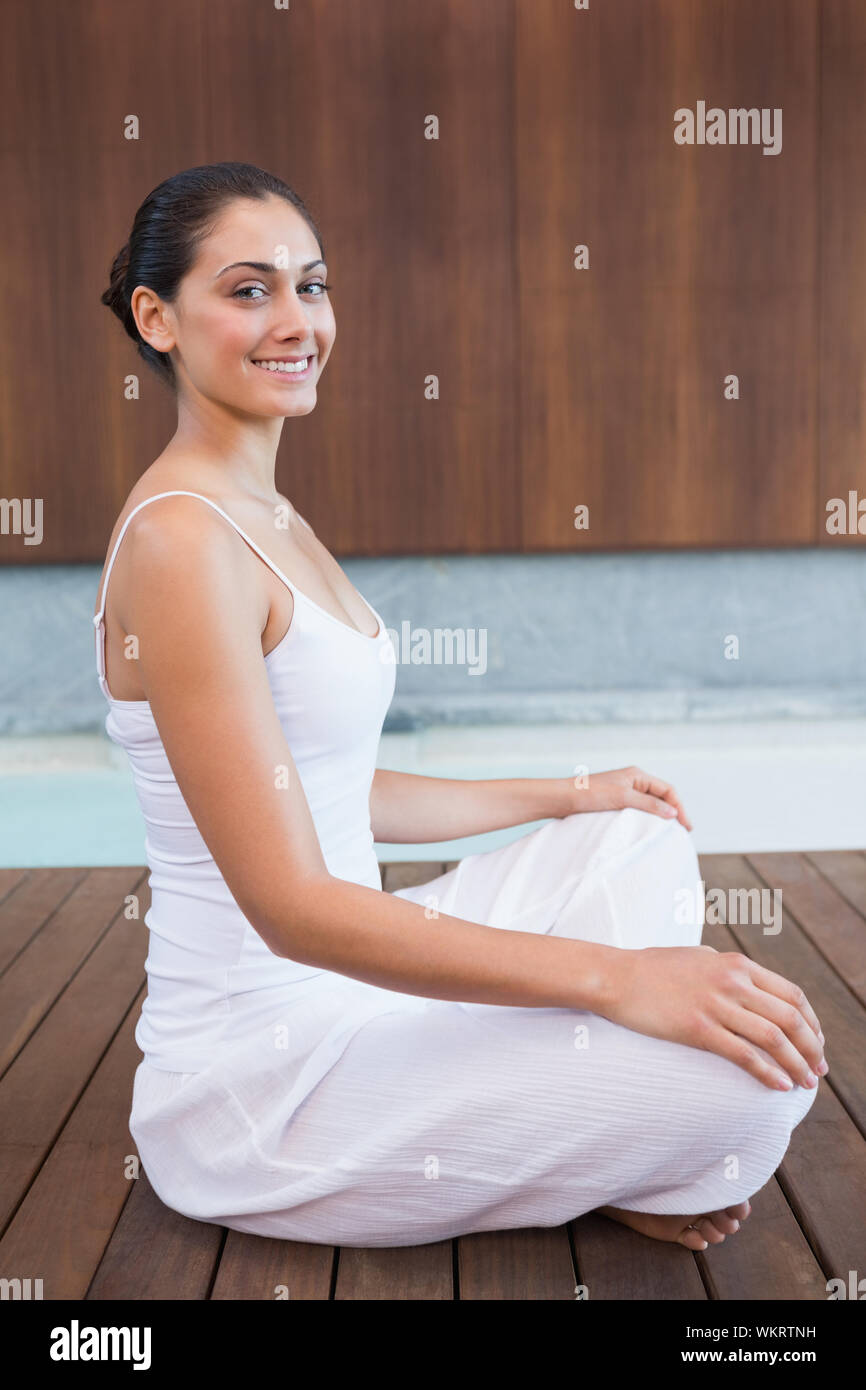 Content brunette en blanc assis en lotus de poser dans les health spa Banque D'Images