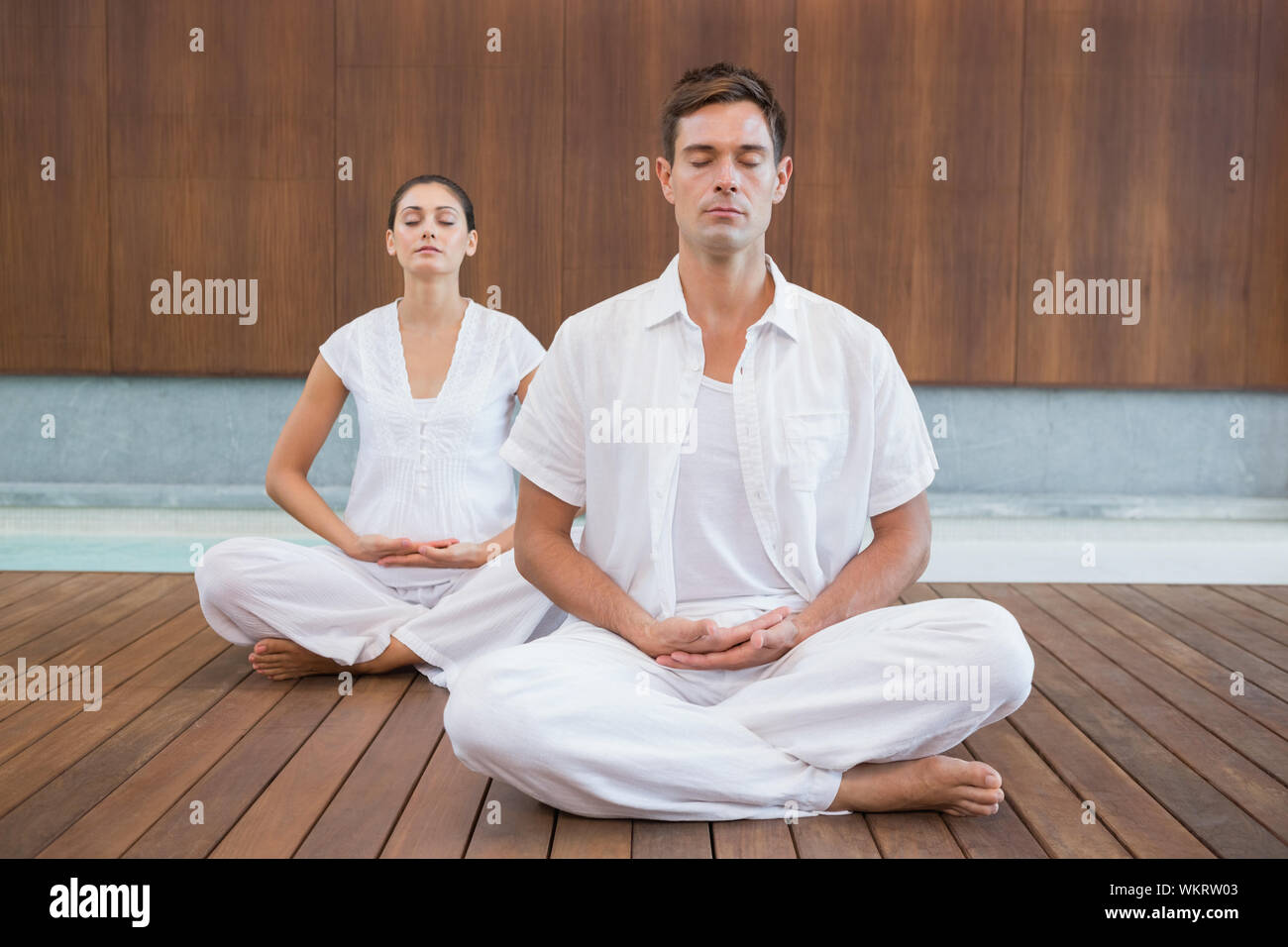 Couple pacifique en blanc assis dans lotus posent ensemble dans health spa Banque D'Images