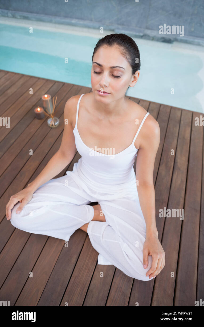 Brunette pacifiques en blanc assis en lotus de poser dans les health spa Banque D'Images