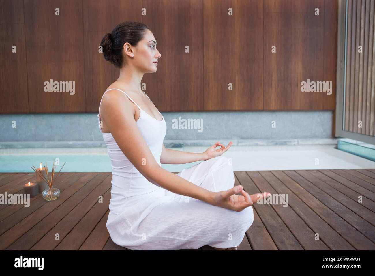 Brunette pacifiques en blanc assis en lotus de poser dans les health spa Banque D'Images
