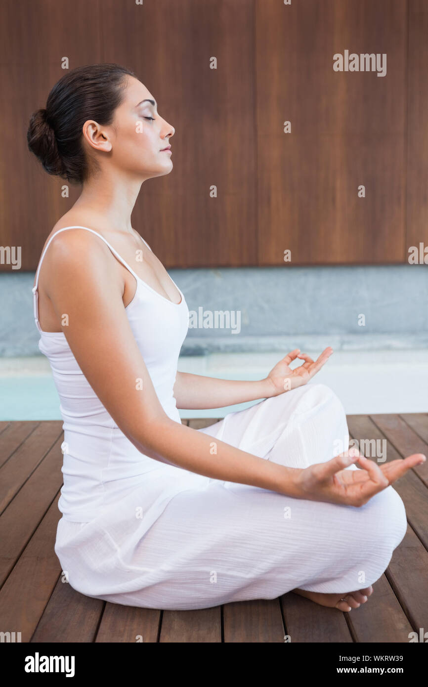 Content brunette en blanc assis en lotus de poser dans les health spa Banque D'Images