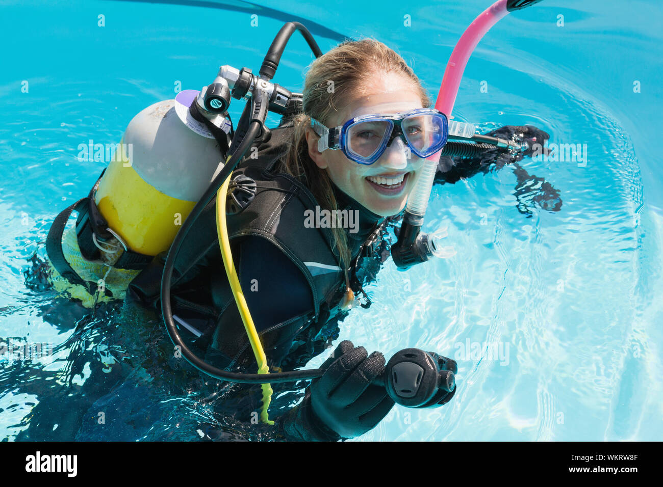 Femme souriante sur la formation de plongée en piscine sur une journée ensoleillée Banque D'Images