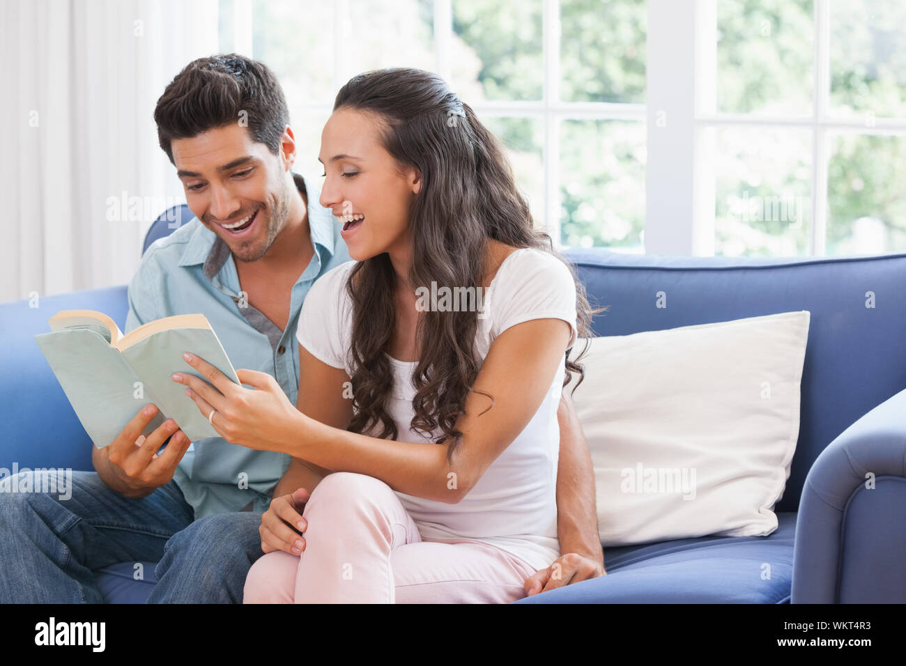 Beau couple reading book sur le canapé à la maison dans la salle de séjour Banque D'Images