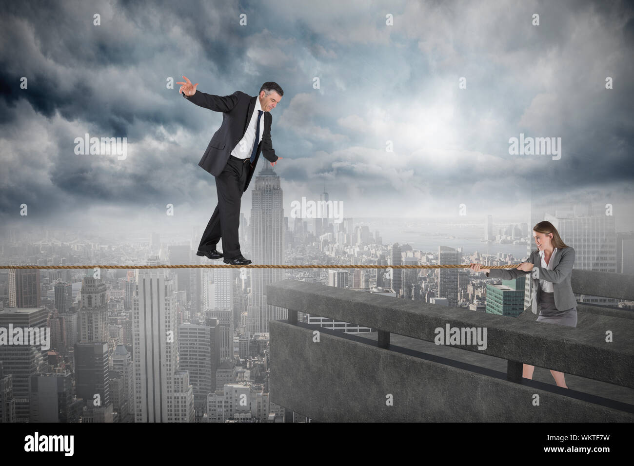 Young businesswoman pulling un fil pour l'homme d'affaires contre un balcon avec vue sur ville Banque D'Images