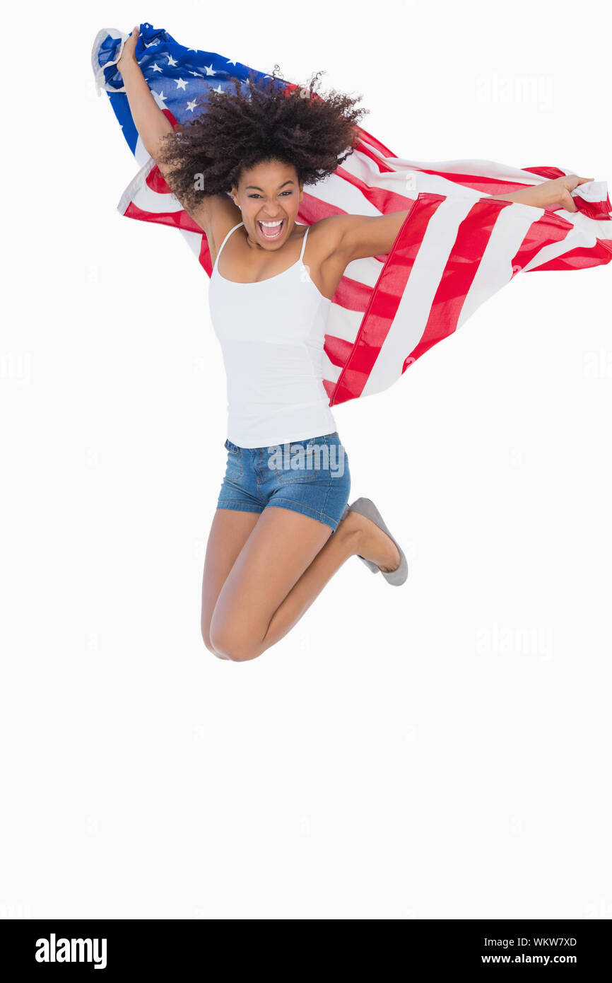 Jolie fille enveloppée de drapeau américain jumping and smiling at camera sur fond blanc Banque D'Images