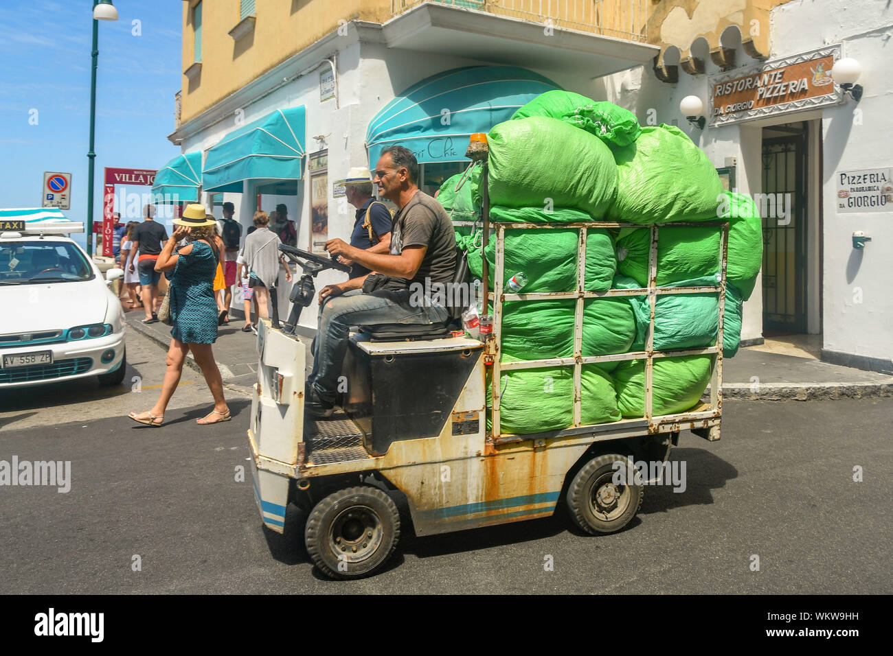 Île de Capri, ITALIE - AOÛT 2019 : Personne qui conduit une petite voiturette électrique transporter des sacs d'ordures par sac de la ville de Capri. Banque D'Images
