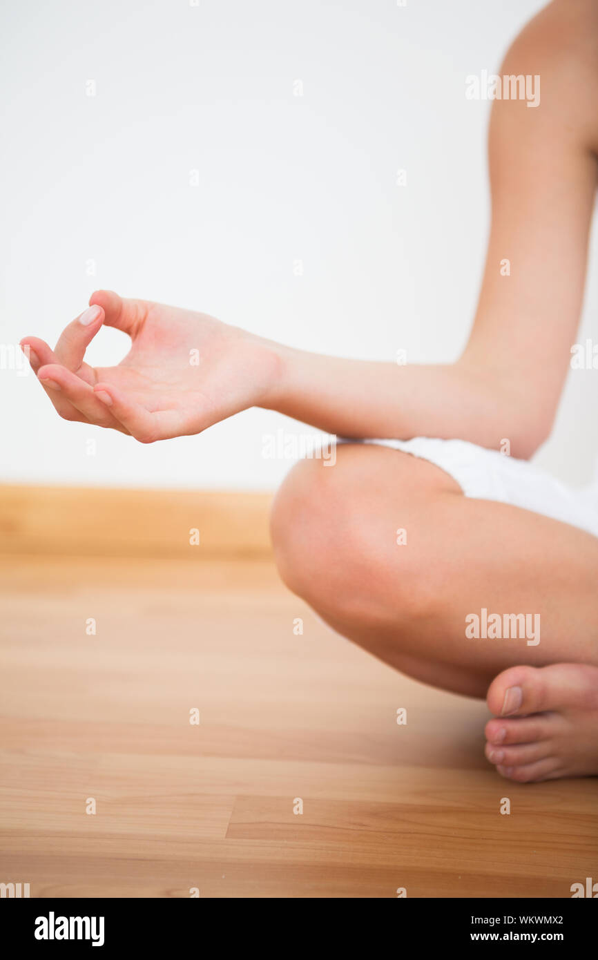 La femme assise en lotus posent à la maison contre un mur blanc Banque D'Images