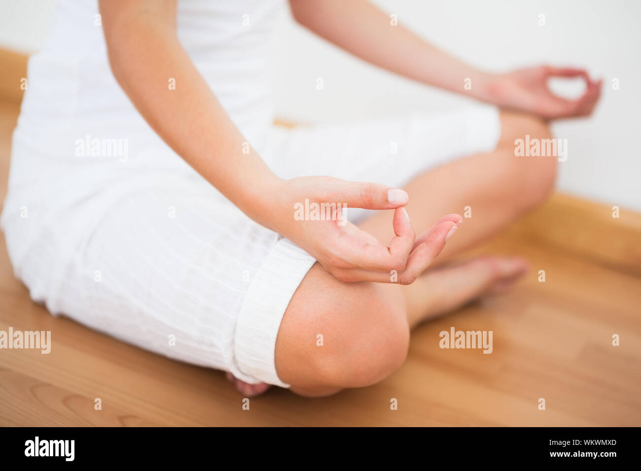La femme assise en lotus posent à la maison contre un mur blanc Banque D'Images