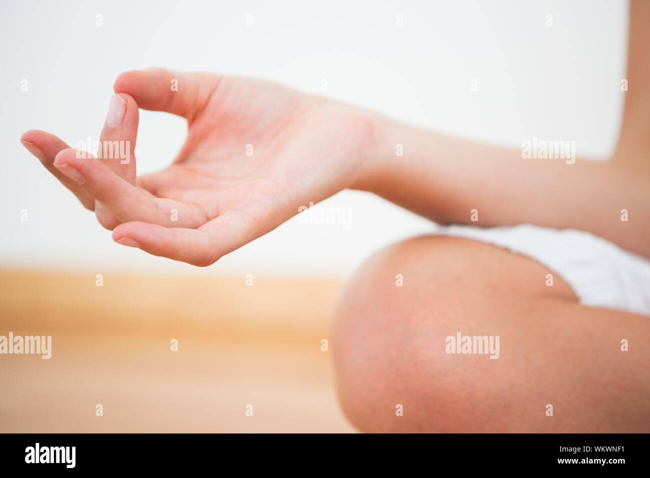 La femme assise en lotus posent à la maison contre un mur blanc Banque D'Images