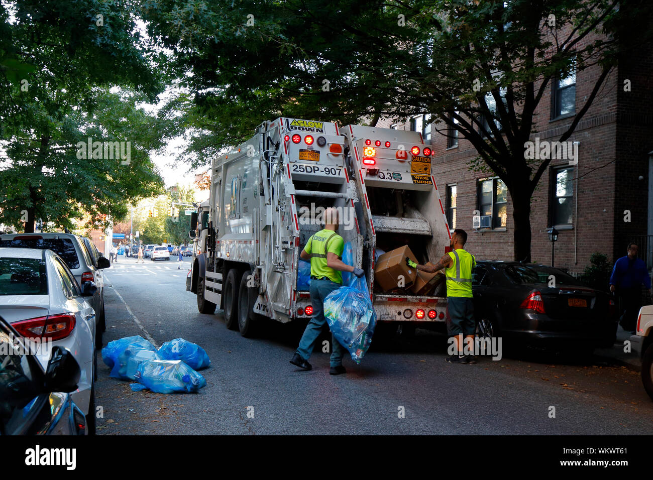 NYC éboueurs charger des sacs poubelles remplis de matières recyclables dans un camion Banque D'Images