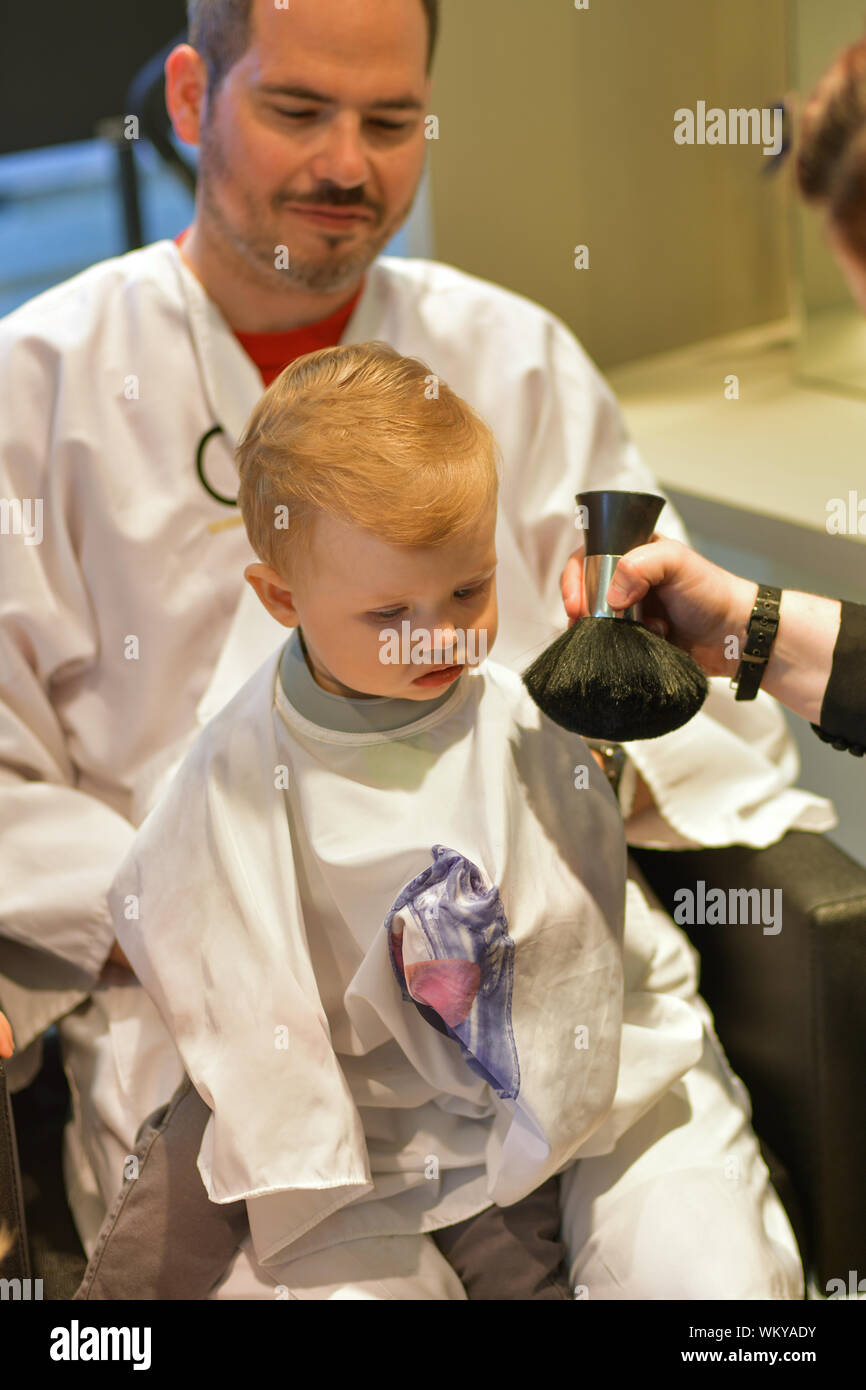 Papa est titulaire d'un petit garçon à la coiffure pour une première coupe Banque D'Images