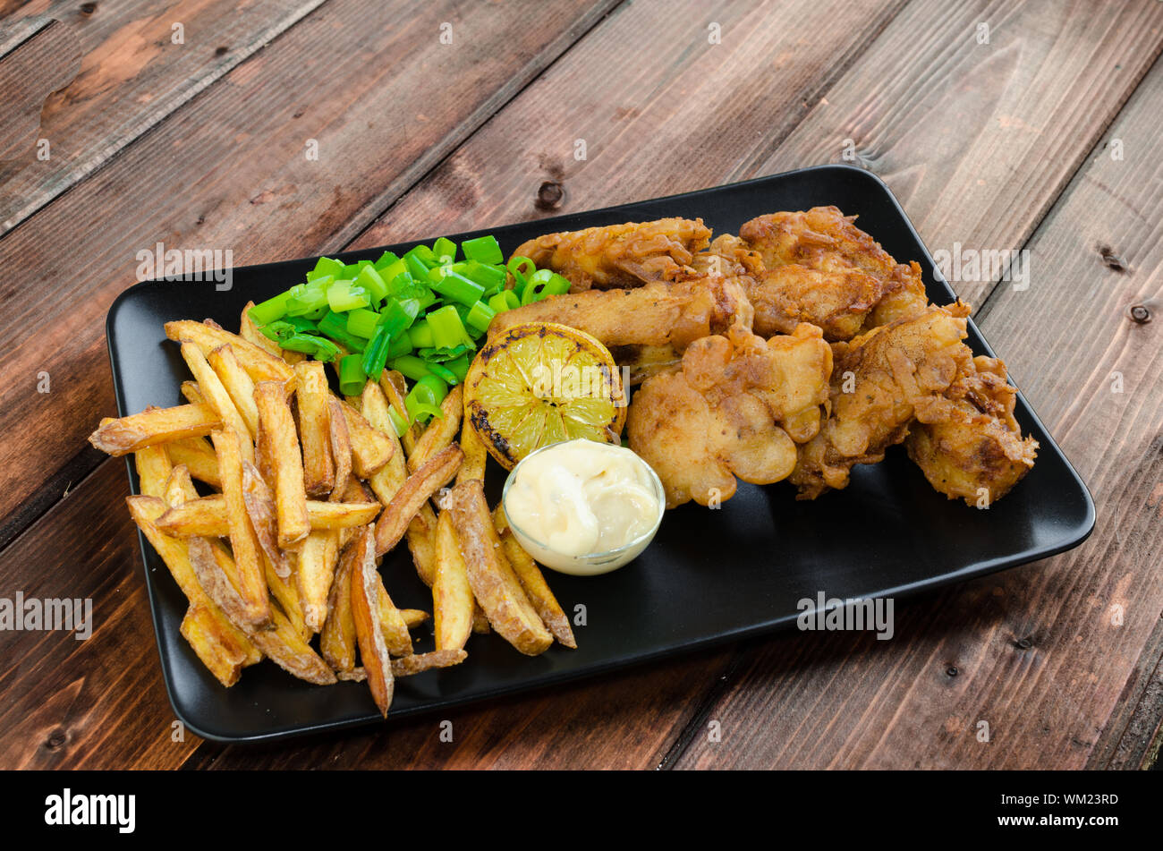 Poisson-frites avec mayonnaise maison sur la plaque noire Banque D'Images