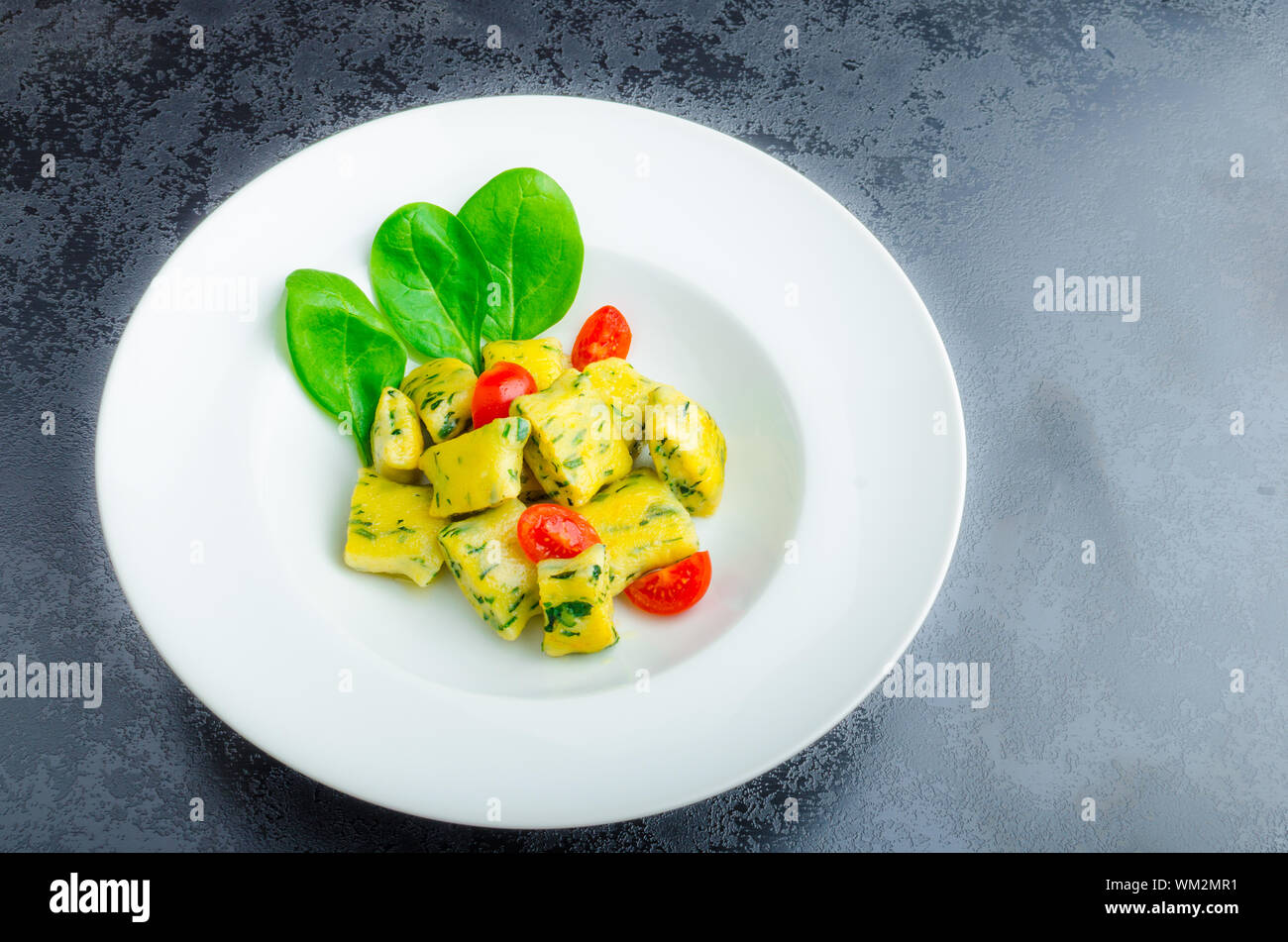 Gnocchi aux épinards avec du beurre fondu et les tomates cerise du jardin Banque D'Images