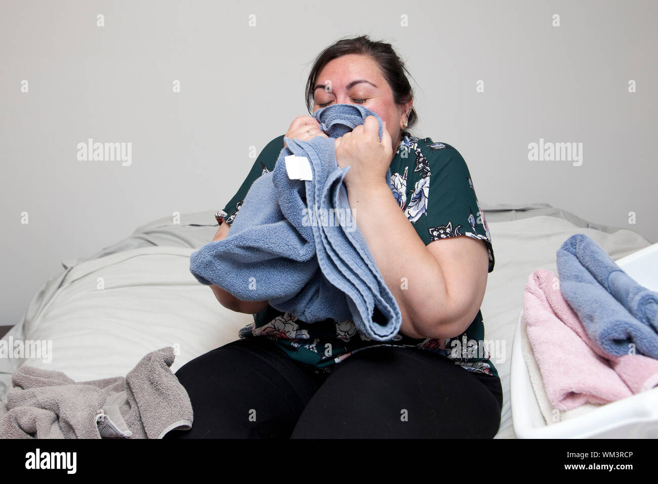 Heureux latina woman est titulaire d'une serviette pliée à son nez et les odeurs Banque D'Images
