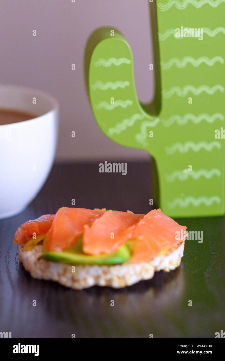 Délicieux saumon fumé et d'avocat frais sur des toasts de pain de riz et une tasse de café. Banque D'Images