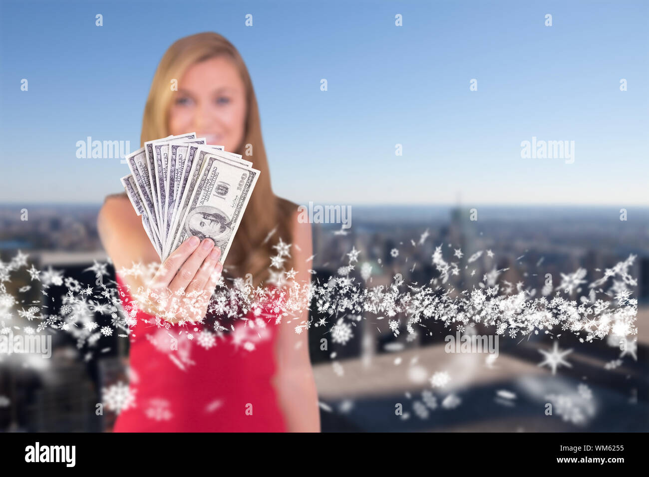 Jolie blonde montrant liasse de paiement contre city skyline Banque D'Images