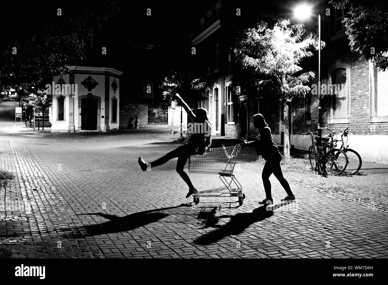 Amis ludique avec panier sur la rue éclairée la nuit Photo Stock - Alamy