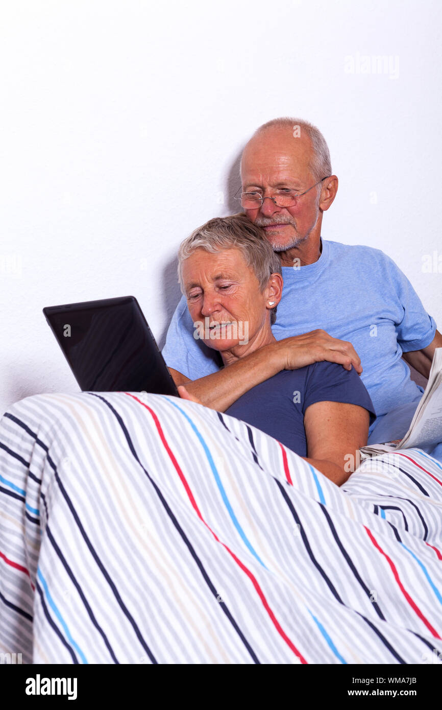 Senior Couple with Tablet et presse au lit Banque D'Images