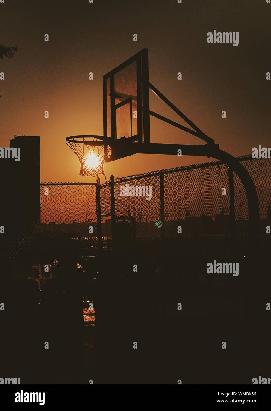 Illusion d'optique de soleil en basket-ball en cour contre le ciel au  coucher du soleil Photo Stock - Alamy