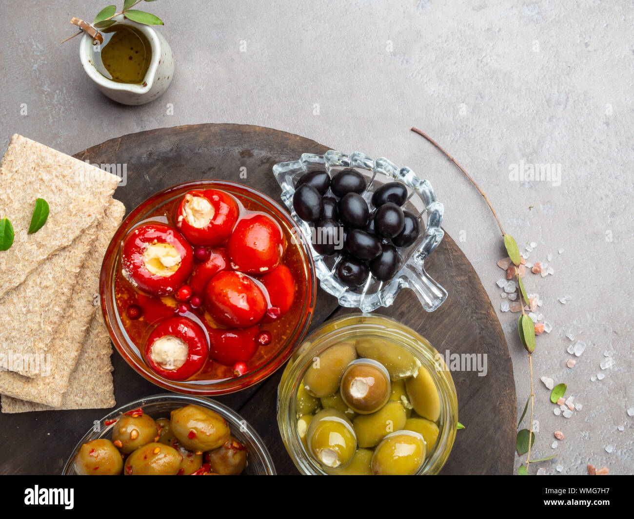 Ingrédients de cuisine italienne avec des craquelins de fond, l'huile d'olive, mini poivrons farcis au fromage, olives et d'herbes sur ardoise gris Banque D'Images
