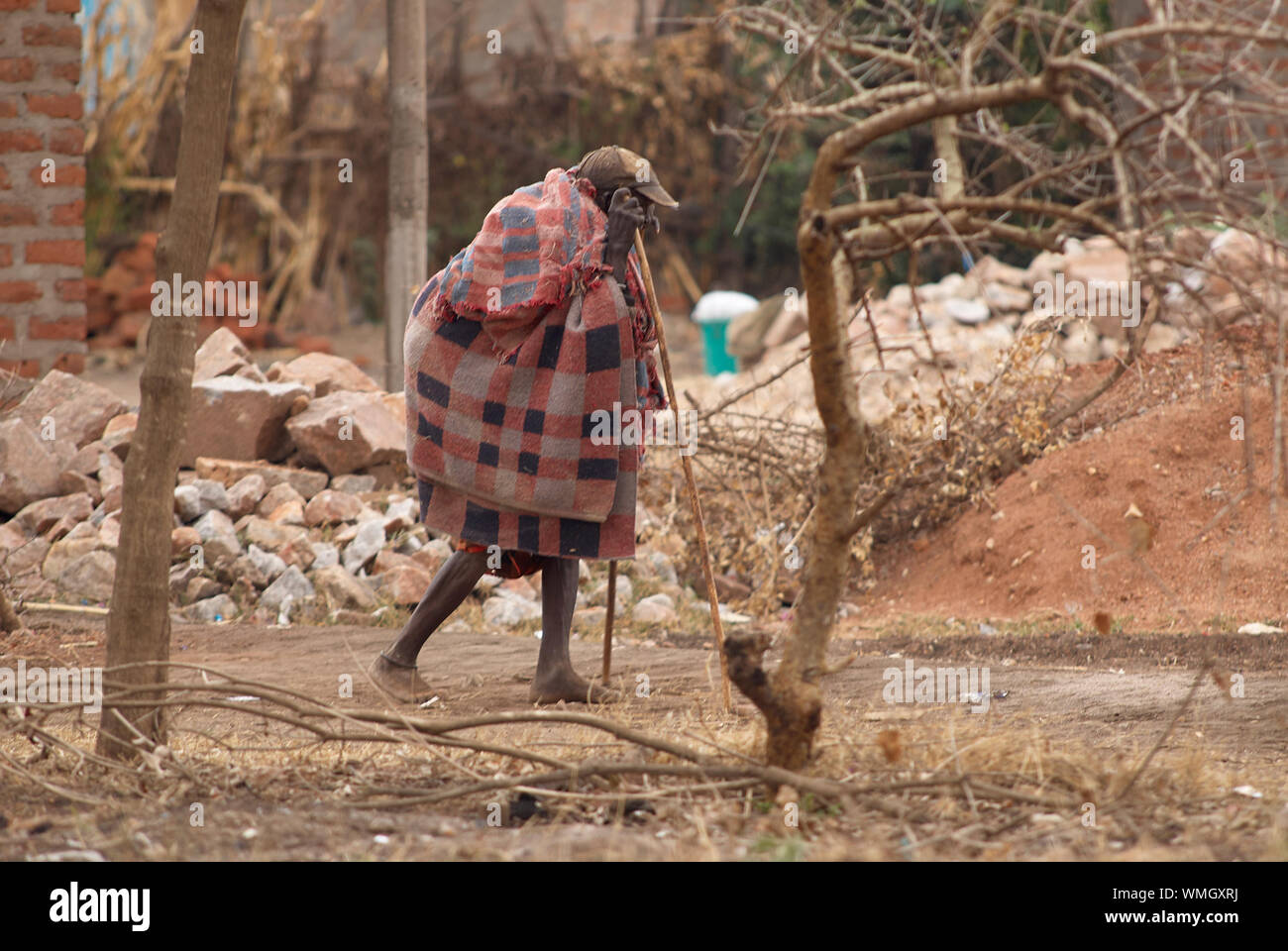 Un vieil homme Massaï, travailler lentement le chemin de sa maison Banque D'Images