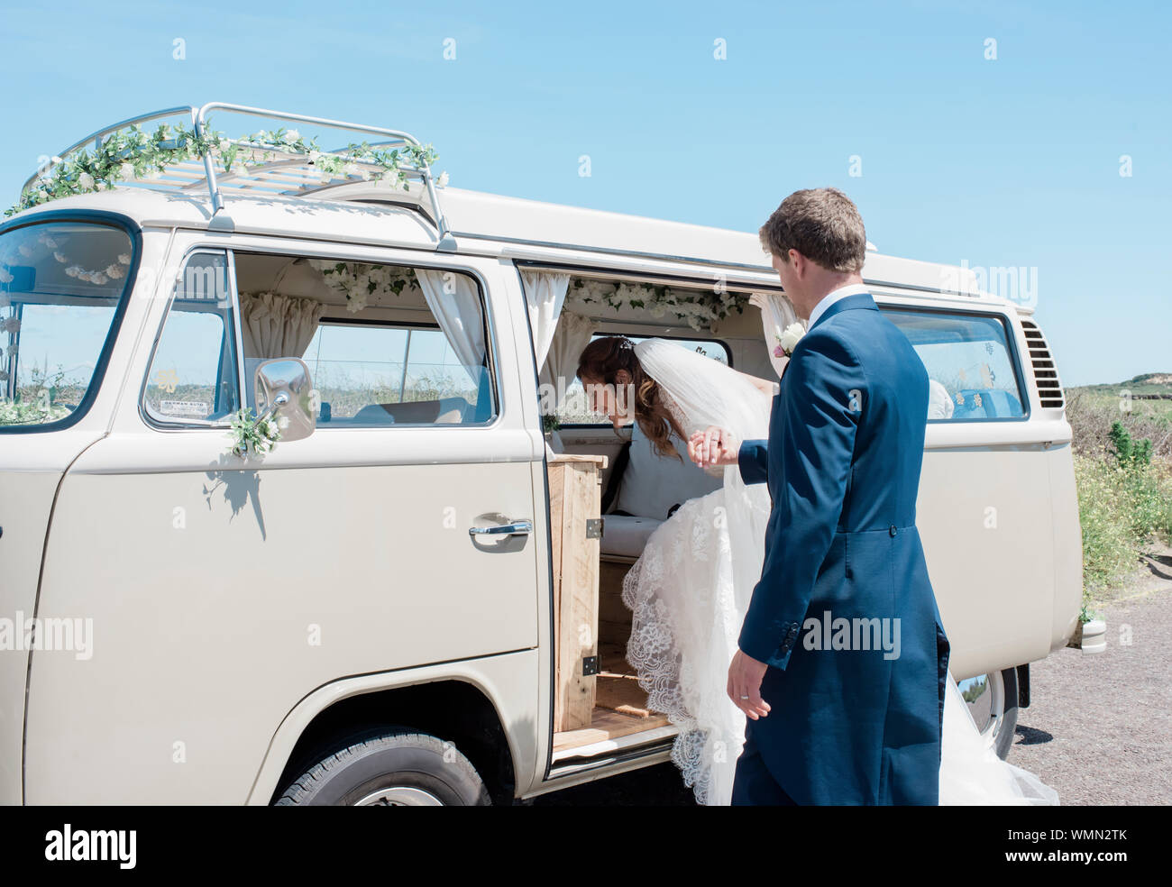 Aider le marié mariée entrer dans un camping-car le jour de leur mariage Banque D'Images
