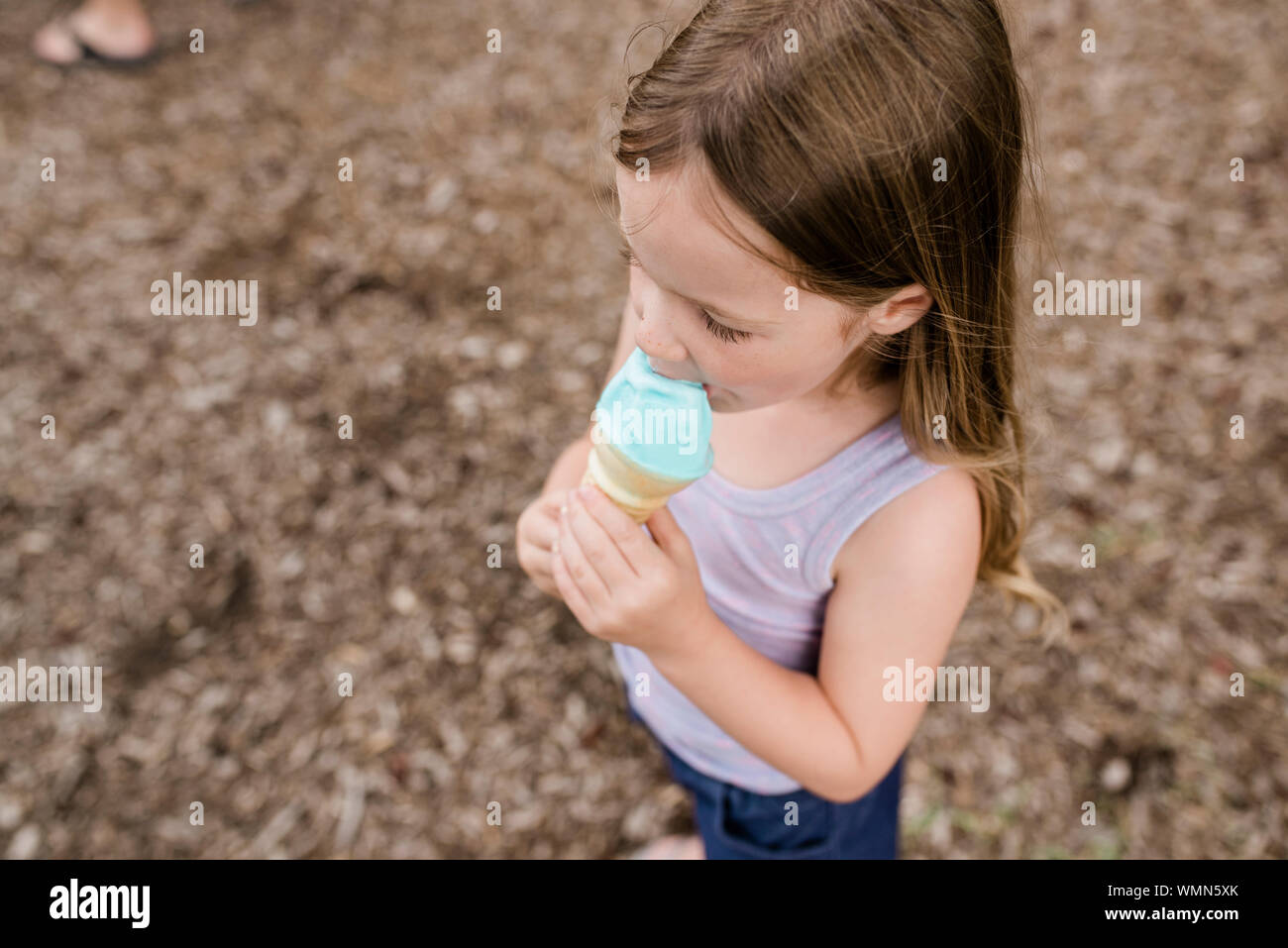 Close up of young girl eating a blue ice cream cone Banque D'Images