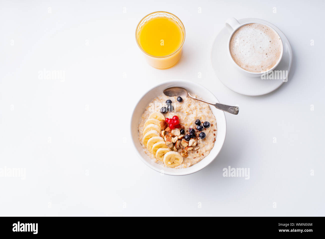 Le petit-déjeuner avec du gruau avec de petits fruits et noix, café et jus d'orange Banque D'Images
