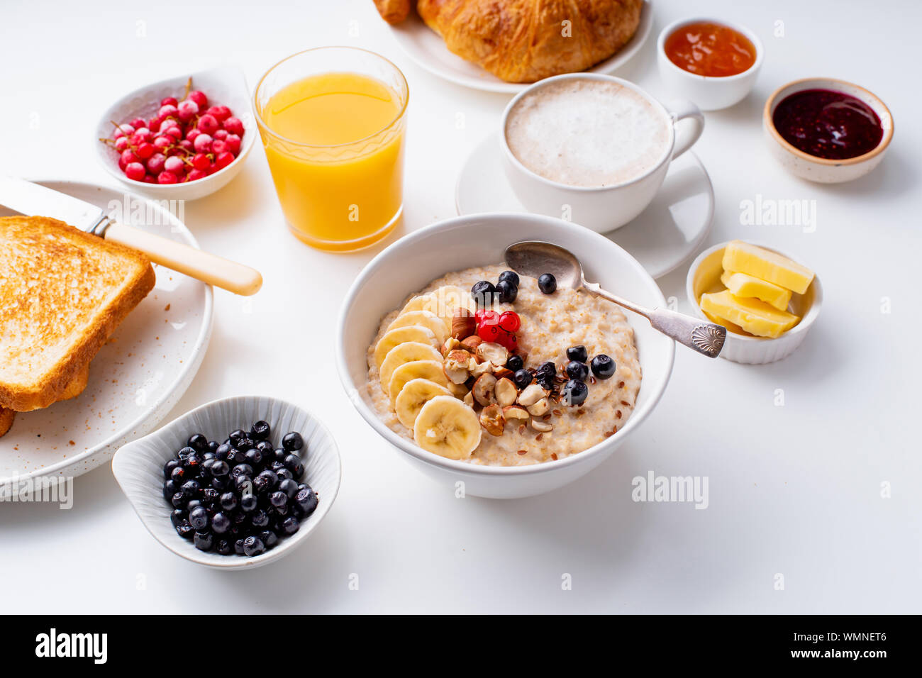 Le petit-déjeuner avec du gruau avec des baies et des noix, des croissants, des toasts avec du beurre et de la confiture, du café et du jus d'orange Banque D'Images