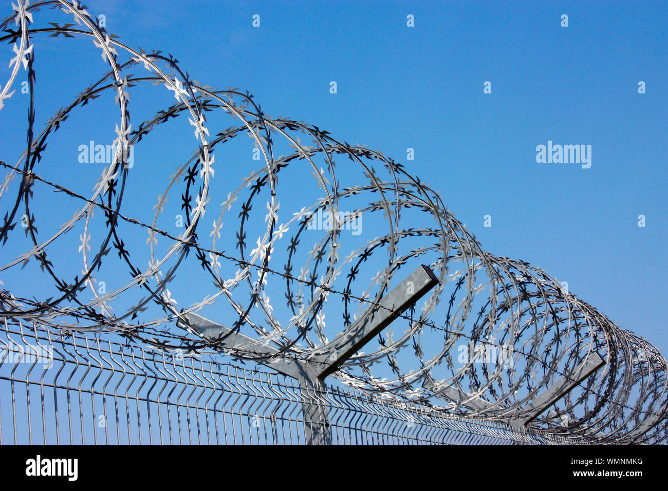 Clôture avec barbelés contre le ciel bleu. Symbole de la liberté d'emprisonnement. Banque D'Images