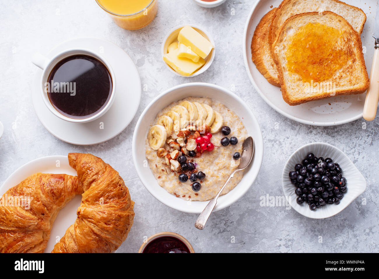 Le petit-déjeuner avec du gruau avec des baies et des noix, des croissants, des toasts avec du beurre et de la confiture, du café et du jus d'orange Banque D'Images