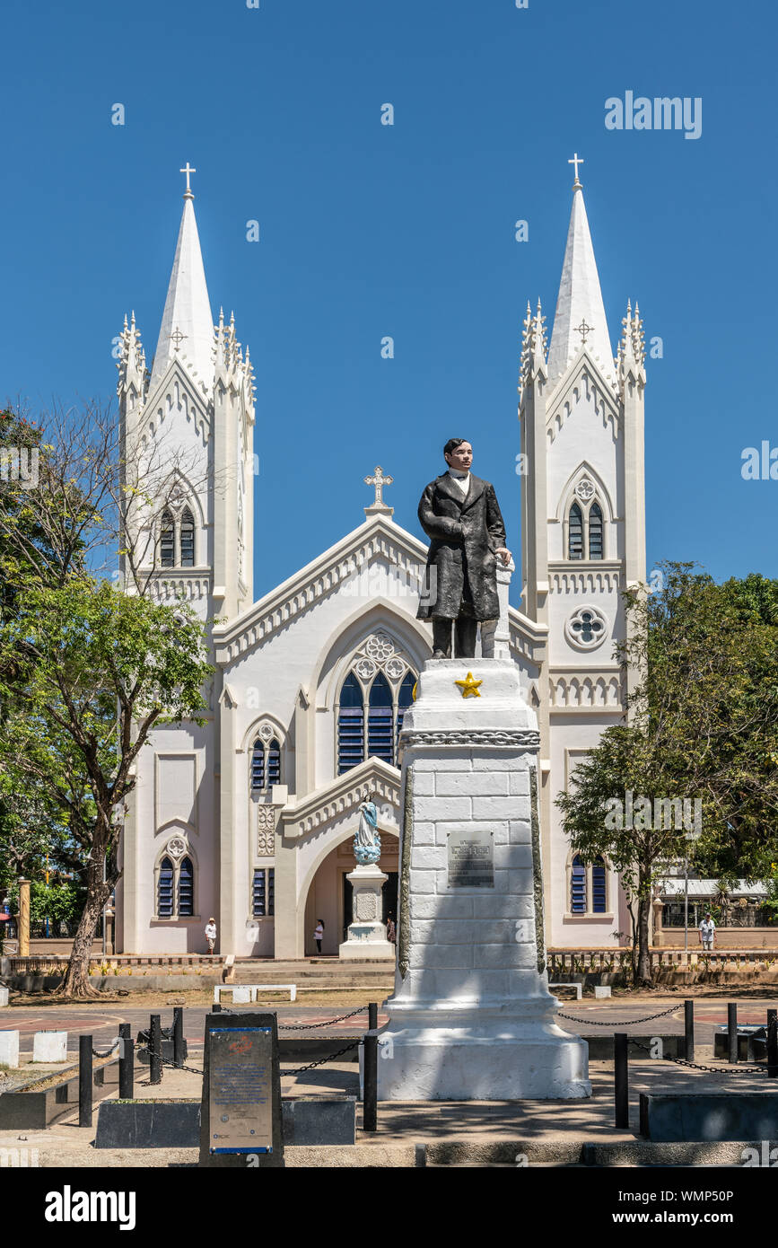 Puerto Princesa, Palawan, Philippines - 3 mars, 2019 : Jose P. Rizal statue in front of White Cathédrale de l'Immaculée Conception entrée avec twin tower Banque D'Images