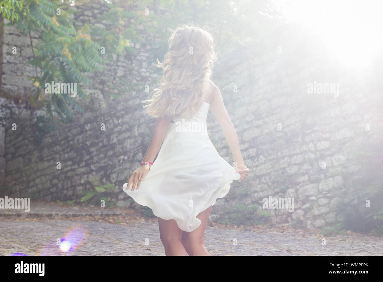 Young woman wearing white dress dancing au parc sur sunny day Banque D'Images