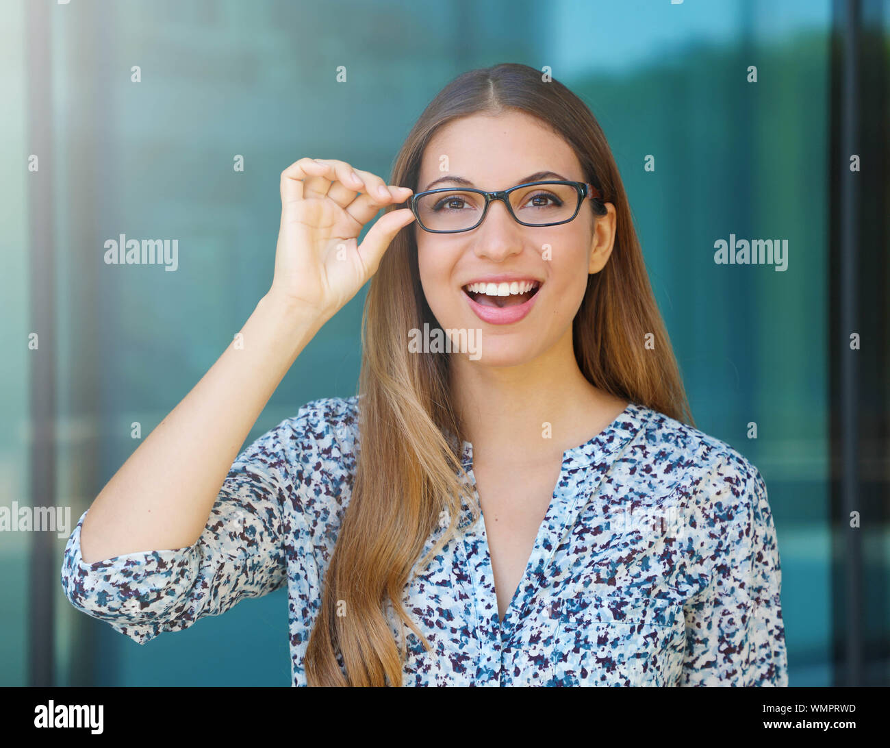 Heureux belle jeune femme détient ses lunettes et regarde à l'extérieur de l'appareil photo. Banque D'Images