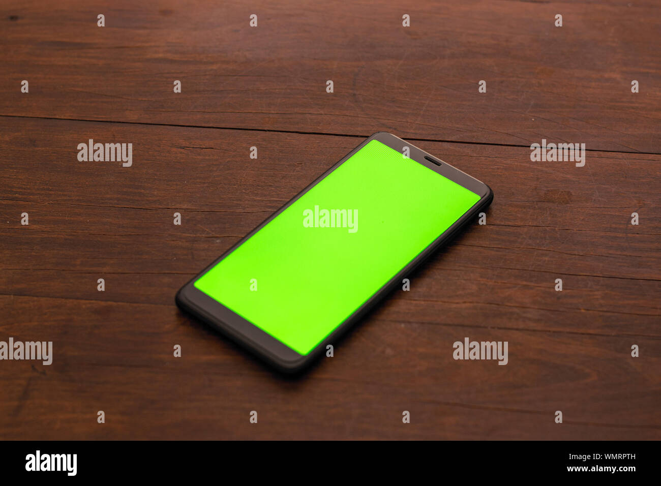 Non identifié noir smartphone avec un écran vert sur un fond de table en bois Banque D'Images